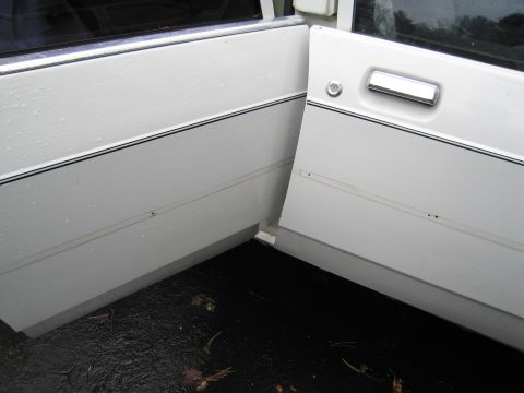 1991 Ford LTD Crown Victoria - The side profile of two white car doors, chrome handles and a black trim line, suggests a 1991 Ford Crown Victoria LTD.