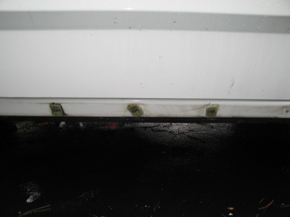 Close-up of white car door with green clips holding trim in place