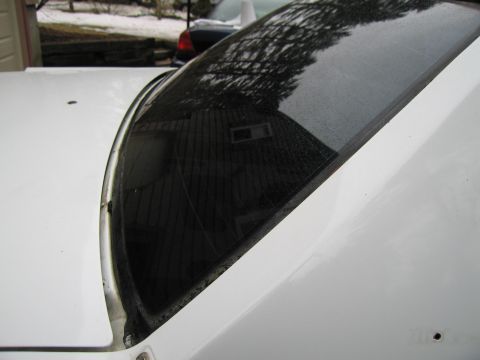 1991 Ford LTD Crown Victoria - Close-up view of a white car's windshield and hood, with reflections of a house and trees.