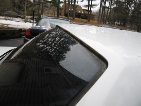 1991 Ford LTD Crown Victoria - Close-up of a white car's roof and rear window, with a dark car in the background.