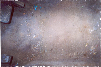 1991 Ford Crown Victoria - The floor of a car interior is covered in dirt and debris, with two pedals visible on the left.