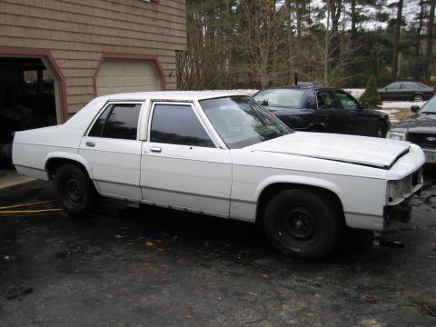 1991 Ford LTD Crown Victoria - White 1991 Ford Crown Victoria LTD is parked outside a garage with other vehicles visible.