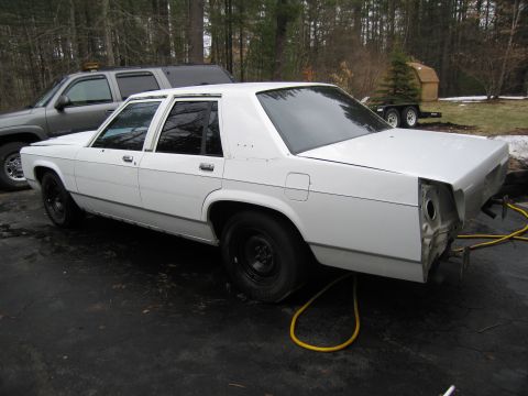 1991 Ford LTD Crown Victoria - This 1991 Ford Crown Victoria LTD is seen from the rear, with its bumper removed, in what appears to be a project or repair setting.