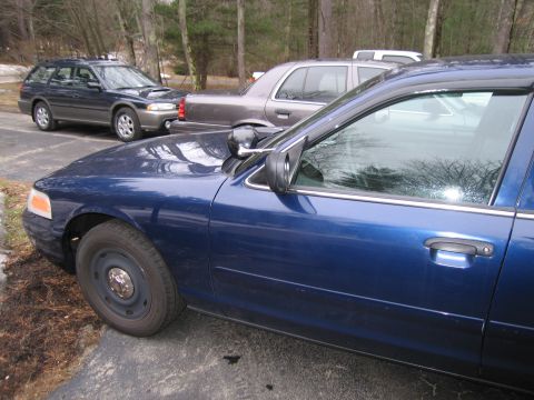 1991 Ford LTD Crown Victoria - Side view of a blue sedan with a police-style mirror light, parked outdoors.