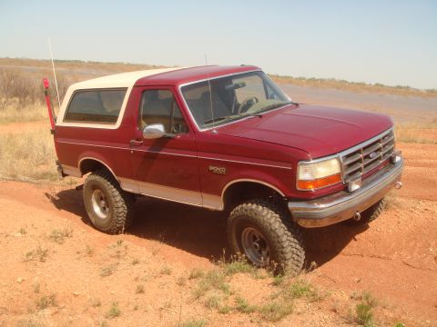 1992 Ford Bronco - 1992 Ford Bronco navigating a dusty, off-road trail with a clear sky overhead.