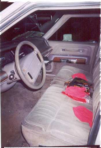 1991 Ford Crown Victoria - The interior of a car is shown, with a focus on the driver's side and passenger seat. Red items are scattered on the seat.