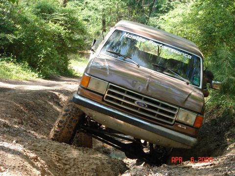 1987 Ford Bronco - This 1987 Ford Bronco is navigating a challenging off-road trail with one wheel lifted high.