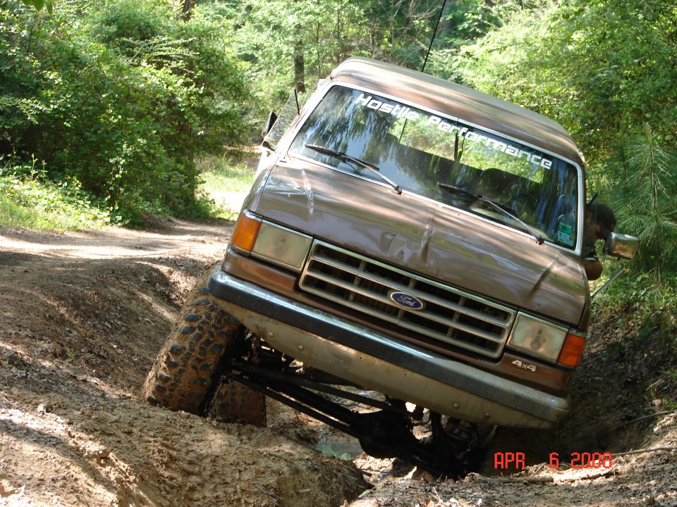 Brown 1987 Ford Bronco climbing a muddy hill on a trail