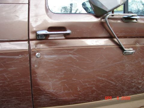 1987 Ford Bronco - Scratched side door panel and side mirror on a brown 1987 Ford Bronco.