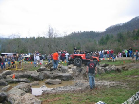 1992 Ford Mustang - An off-road buggy attempts a difficult rock crawl course as a crowd observes the event.
