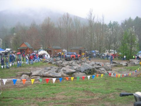 1992 Ford Mustang - An off-road event with a bright orange vehicle attempting a rocky obstacle course, while onlookers watch from the sidelines.