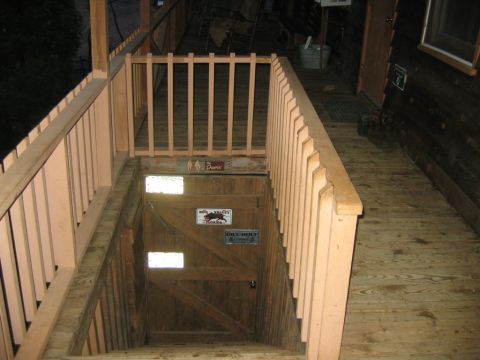 1992 Ford Mustang - A wooden staircase descends to a door adorned with various signs, set within a rustic wooden structure.