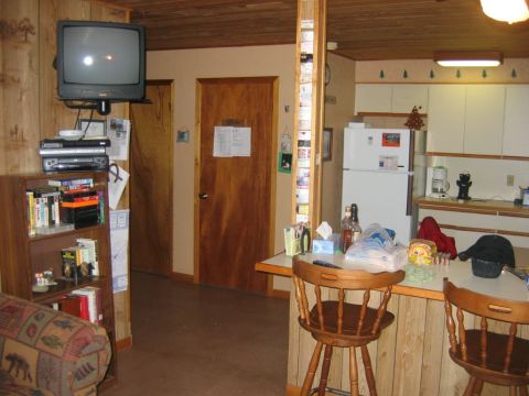 1992 Ford Mustang - Interior view of a room showing a television, bookshelf, and a kitchen area with a refrigerator and counter space.