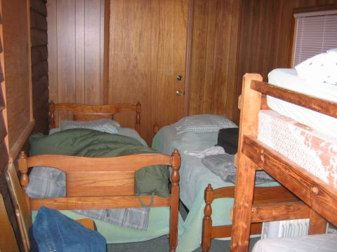 1992 Ford Mustang - A bedroom scene shows multiple beds with wooden frames and bedding, set against wood-paneled walls.