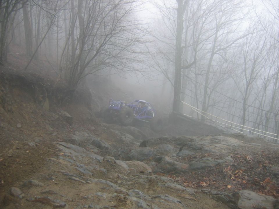 Blue off-road buggy navigating a rocky, foggy slope