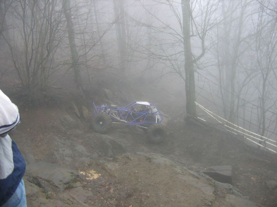 purple off-road buggy climbing a muddy hill in foggy woods