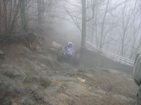 1992 Ford Mustang - A purple off-road vehicle descends a treacherous, muddy slope surrounded by bare trees and fog.