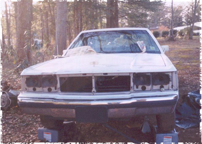 1991 Ford Crown Victoria - This 1991 Ford Crown Victoria is shown from the front, missing its headlights and grille, and is supported by jack stands.