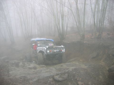 1992 Ford Mustang - A classic Ford Bronco tackles a challenging off-road course amidst a foggy forest landscape.