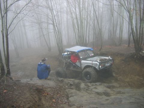1992 Ford Mustang - A modified off-road vehicle navigates a challenging muddy terrain in a dense, fog-covered forest.