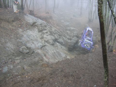1992 Ford Mustang - A purple off-road buggy attempts to climb a treacherous, muddy, and rocky slope in a misty wooded area.