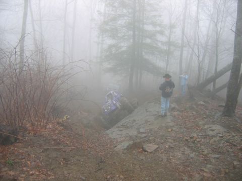 1992 Ford Mustang - An off-road vehicle navigates a challenging muddy incline amidst a foggy forest landscape.