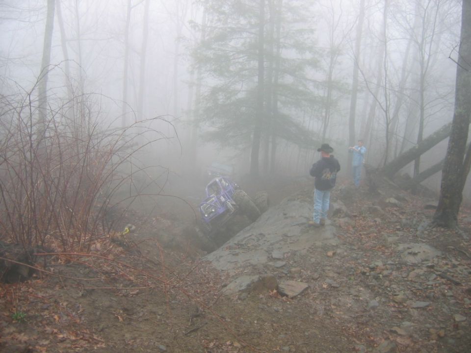 Purple off-road vehicle on a muddy hill in fog