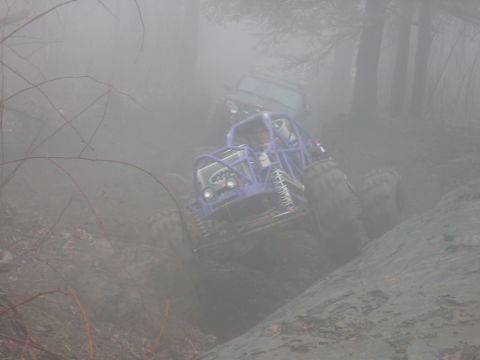 1992 Ford Mustang - Two off-road vehicles navigate a challenging muddy terrain in foggy conditions.