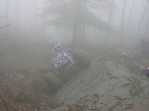 1992 Ford Mustang - A custom off-road buggy navigates a challenging rocky and muddy terrain in foggy conditions, with another vehicle visible in the background.