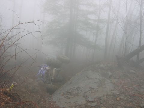 1992 Ford Mustang - An off-road vehicle is stuck in a muddy ditch in a foggy forest environment.