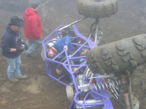 1992 Ford Mustang - An off-road buggy has overturned, with several people gathered around the scene.