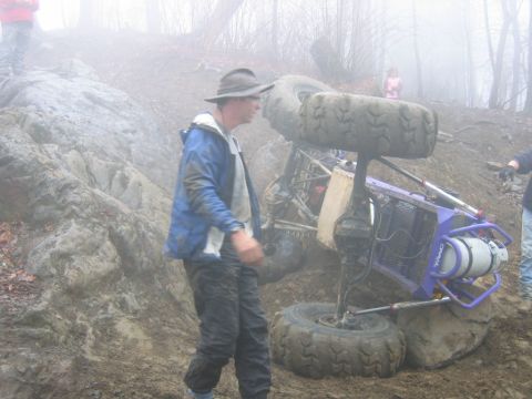 1992 Ford Mustang - An off-road buggy has tipped over on a muddy, rocky incline in foggy conditions.