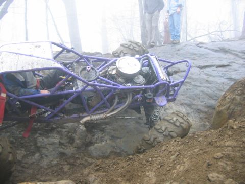 1992 Ford Mustang - Off-road buggy navigates a challenging muddy terrain with spectators observing the action.