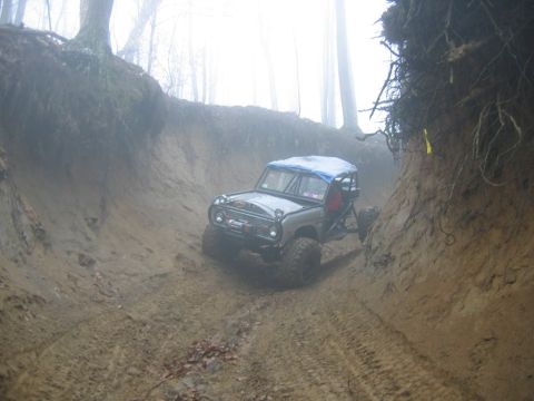 1992 Ford Mustang - Modified off-road vehicle descends a challenging muddy trail with steep dirt walls.