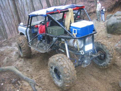 1992 Ford Mustang - Custom off-road buggy navigates a challenging muddy terrain with steep inclines.