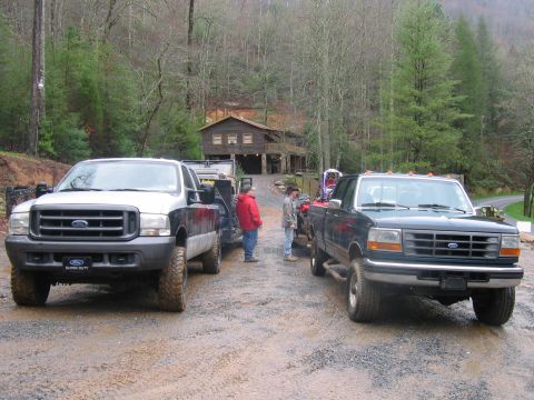 1992 Ford Mustang - Two Ford F-Series trucks are parked on a gravel road in front of a house.