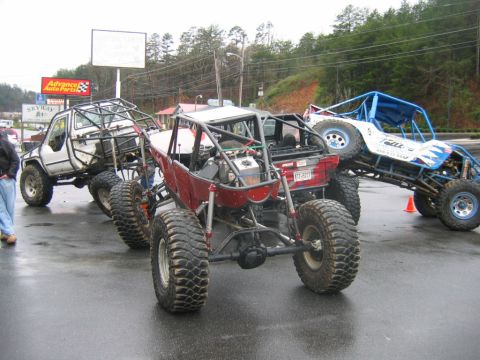 1992 Ford Mustang - Custom off-road buggies are parked together on a wet surface, possibly after an event.
