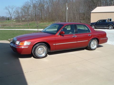 1999 Mercury Grand Marquis - This red 1999 Mercury Grand Marquis is shown in a 3/4 front view, parked on a concrete driveway.