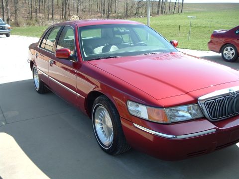 1999 Mercury Grand Marquis - Red 1999 Mercury Grand Marquis sedan with chrome grille and trim, parked outdoors.