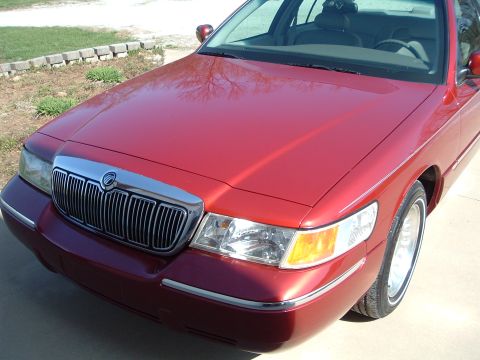 1999 Mercury Grand Marquis - The front grille and headlights of a red 1999 Mercury Grand Marquis are visible.