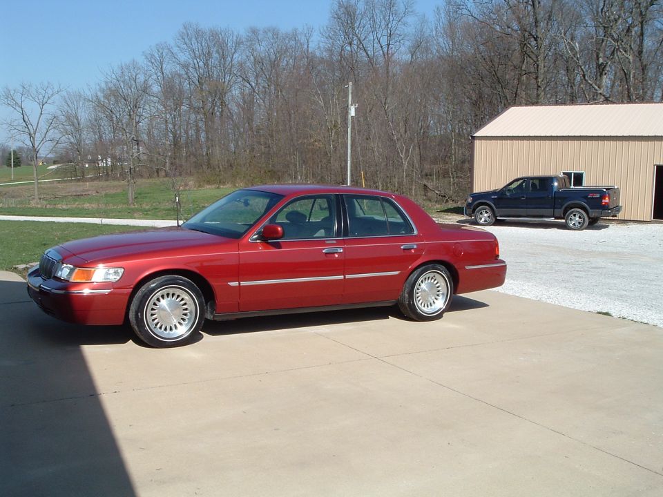 Red 1999 Mercury Grand Marquis sedan parked in driveway, 3q-front view