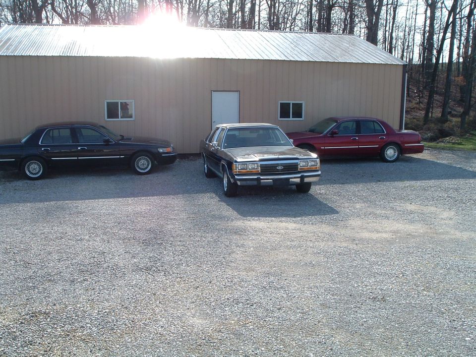 Three sedans parked in front of a building, one is a dark sedan, another is a silver sedan, and the third is a red sedan