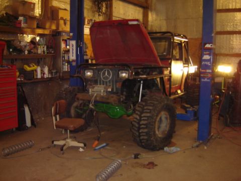1992 Ford Bronco - An off-road vehicle with a Mercedes-Benz emblem on the grille is parked in a garage with its hood open.