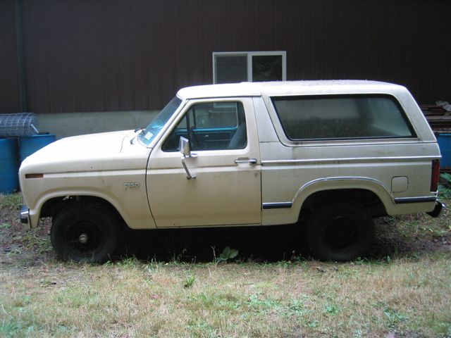 Side view of a cream-colored Ford Bronco. It has black wheels and a chrome trim line