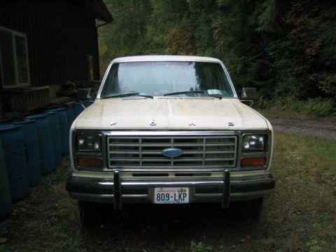 1978 Ford Bronco - A cream-colored 1978 Ford Bronco is parked in front of a building with trees in the background.