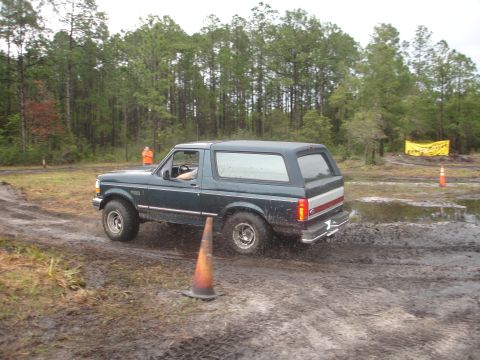 1989 Ford Bronco - A Ford Bronco navigates a muddy off-road course during an event.