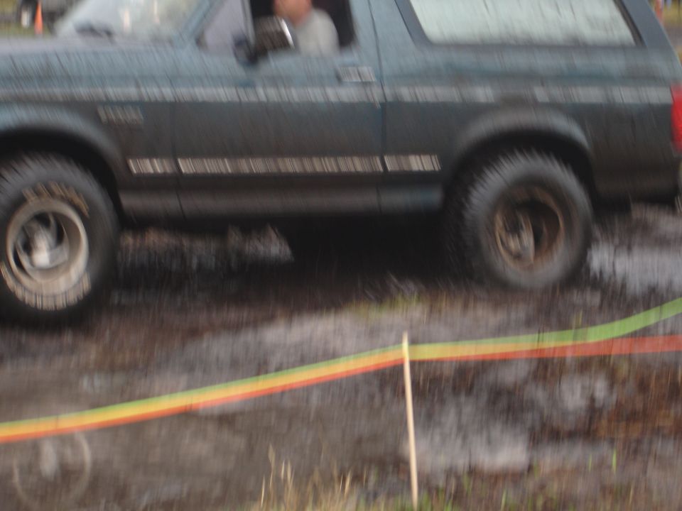 Side view of a 1989 Ford Bronco driving through mud
