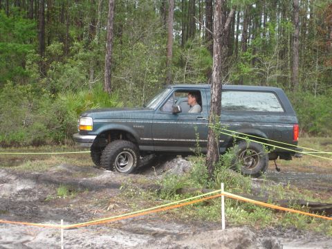 1989 Ford Bronco - Ford Bronco navigates a challenging off-road course in a wooded area.