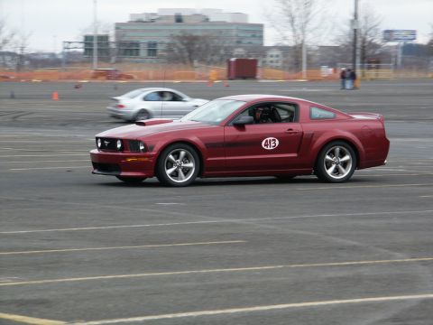 2001 Mercury Grand Marquis - Red Ford Mustang with racing number 413 participates in an event on a track.