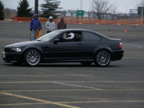 2001 Mercury Grand Marquis - A black coupe is seen from the side on a paved surface, with spectators in the background.
